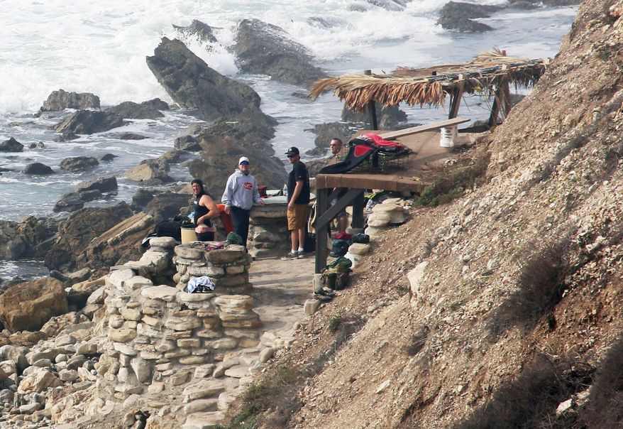 FILE - In this Jan. 22, 2016, file photo people stand at a stone structure at Rocky Point in Lunada Bay in the tony, seaside city of Palos Verdes Estates, Calif. The days are numbered for the "Stone Fort," created by a territorial group of surfers known as the Bay Boys, erected illegally decades ago as part of their sustained battle to keep rival wave-riders from some of the best breaks in Southern California. The city, under pressure from the California Coastal Commission and others, on Tuesday, July 12, 2016,ordered the structure torn down amid complaints that its only purpose is as a staging area from which the Bay Boys can gather to harass other surfers. (Charles Bennett/Long Beach Press-Telegram via AP, File)