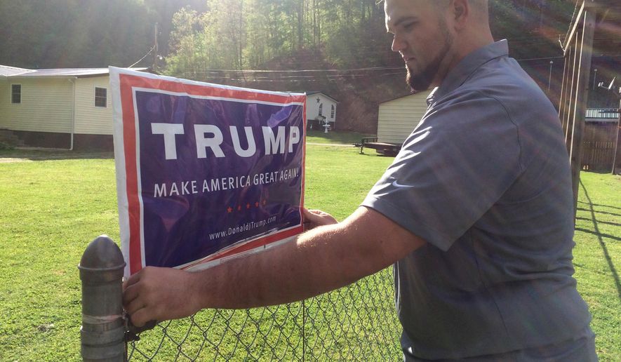 ADVANCE FOR USE MONDAY, JULY 18, 2016 AND THEREAFTER-Billy Prater, 27 adjusts a Donald Trump sign on his fence in Beech Creek, W.Va., in Mingo County on April 28, 2016. Laid off from the mines, he had been out of work for more than a year. Now he works for the railroad, but the major customer is the collapsing coal industry so his work is unsteady. He was a registered Democrat from a family of diehard Democrats. But when he hung the Trump sign, his neighbors started calling and sending him messages, asking where he got it and how to get their own. "Everybody on this creek wants one," he said. "He's honest. He says thing that he probably shouldn't say. We respect that, because it means he's not buttering us up." (AP Photo/Claire Galofaro)