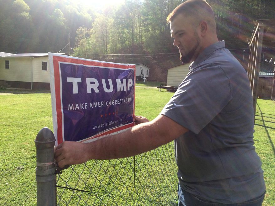 ADVANCE FOR USE MONDAY, JULY 18, 2016 AND THEREAFTER-Billy Prater, 27 adjusts a Donald Trump sign on his fence in Beech Creek, W.Va., in Mingo County on April 28, 2016. Laid off from the mines, he had been out of work for more than a year. Now he works for the railroad, but the major customer is the collapsing coal industry so his work is unsteady. He was a registered Democrat from a family of diehard Democrats. But when he hung the Trump sign, his neighbors started calling and sending him messages, asking where he got it and how to get their own. "Everybody on this creek wants one," he said. "He's honest. He says thing that he probably shouldn't say. We respect that, because it means he's not buttering us up." (AP Photo/Claire Galofaro)