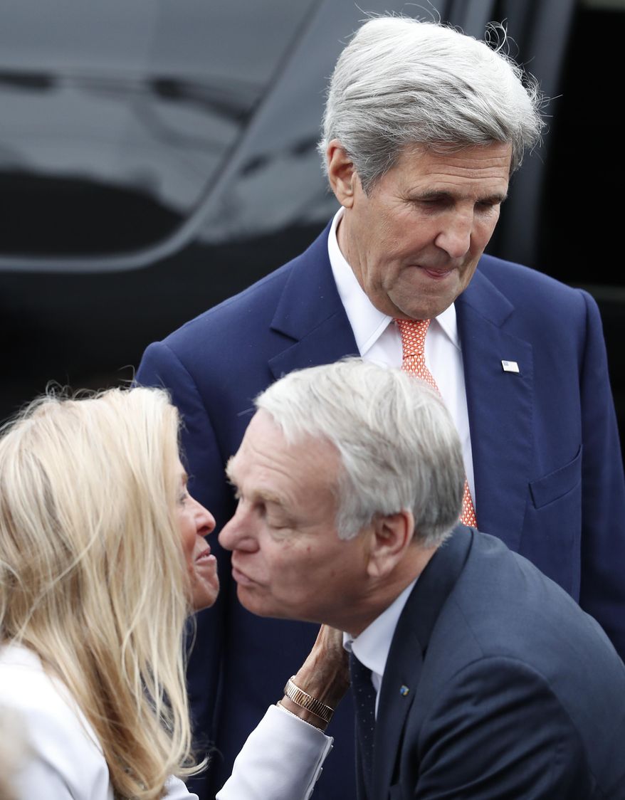 U.S Secretary of State John Kerry, top, looks down as French Foreign Minister Jean-Marc Ayrault kisses U.S ambassador to France Jane Hartley on the Champs Elysees avenue before the Bastille Day Parade in Paris, Thursday, July 14, 2016. (AP Photo/Francois Mori)