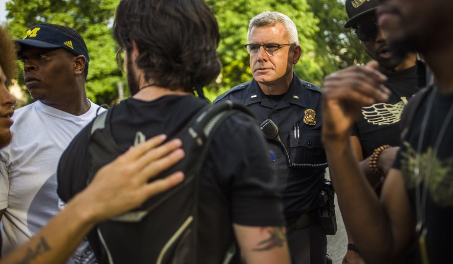 In this Wednesday, July 13, 2016 photo, Ann Arbor police officer Lyle Sartori speaks with protest organizers as they prepare to march through downtown Ann Arbor, escorted by Ann Arbor police vehicles, during a protest against police brutality, in Ann Arbor, Mich. (Katy Kildee/The Ann Arbor News via AP)