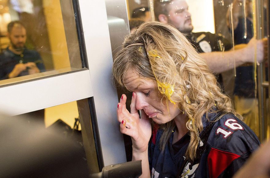 A woman wipes egg off her face after being pursued by protesters while leaving Republican presidential candidate Donald Trump's campaign rally in San Jose, California, June 2, 2016. (AP Photo/Noah Berger) ** FILE **