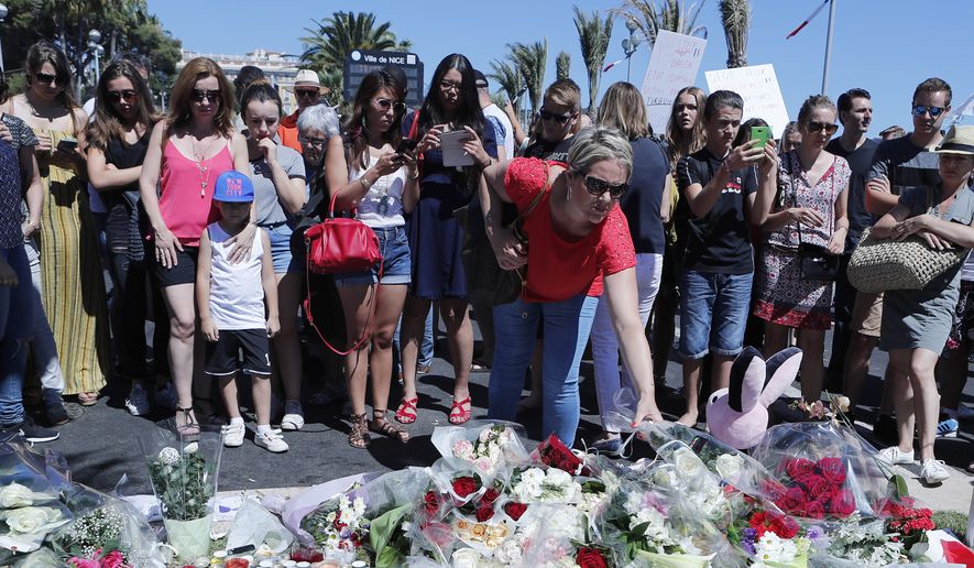 A woman puts flowers near the scene where a truck mowed through revelers in Nice, southern France, Friday, July 15, 2016.  A large truck mowed through revelers gathered for Bastille Day fireworks in Nice, killing more than 80 people and sending people fleeing into the sea as it bore down for more than a mile along the Riviera city&#x27;s famed waterfront promenade. (AP Photo/Francois Mori)