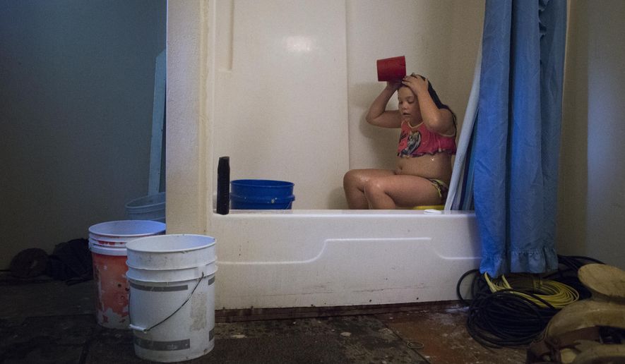 ADVANCE FOR USE SUNDAY, JULY 17 - In this photo taken June 30, 2016, Angelina Garcia, 9, bathes with rain water collected on buckets by her grandfather at their property in New King's Colony subdivision in Montgomery County, near New Caney, Texas. The family depends on bottled water and rain to shower and bathe because their home doesn't receive water service. (Marie D. De Jesus/Houston Chronicle via AP)