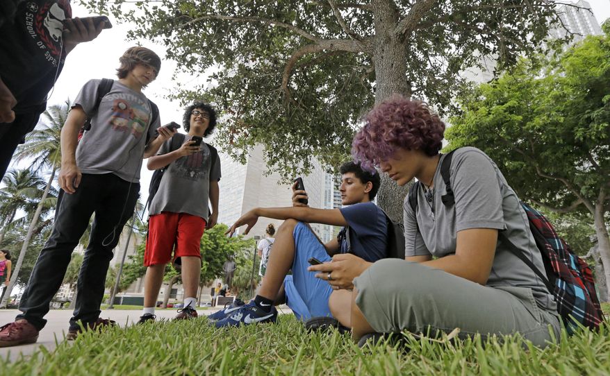 In this Tuesday, July 12, 2016, photo, Pokemon Go players Ana Valentina Ojeda, right, and Jaeden Valdespino, second from right, check their smartphones as they look for Pokemon at Bayfront Park in downtown Miami as the "Pokemon Go" craze has sent legions of players hiking around cities and battling with "pocket monsters" on their smartphones. (AP Photo/Alan Diaz) **FILE**