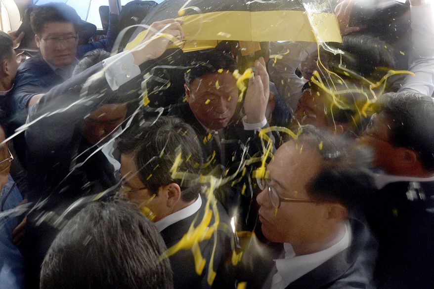 South Korean Prime Minister Hwang Kyo-ahn, bottom center, is shielded by his bodyguards from eggs thrown by residents at Seongju County Office, South Korea, Friday, July 15, 2016. Angry residents in a rural South Korean town have thrown raw eggs and water bottles at the prime minister to protest a plan to deploy a U.S. missile defense system in their neighborhood. (Kang Jong-min/Newsis via AP)