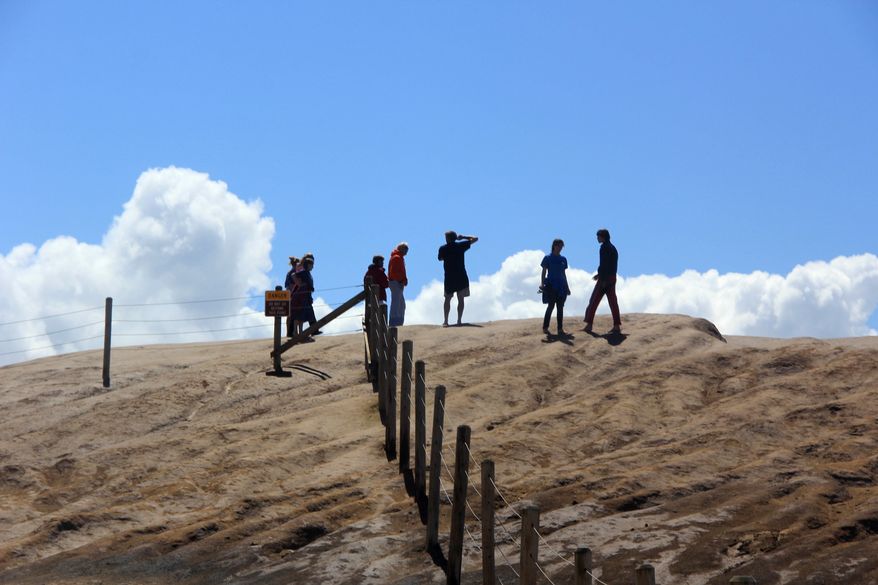 In this photo taken June 29, 2016, visitors walk past the fence guarding the bluffs at Cape Kiwanda State Natural Area in Cloverdale, Ore. Everyone from photographers to families ignore warnings in order to get the perfect photo at the Oregon coast’s deadliest cape, where six people have died in the last 18 months. (Zach Urness/Statesman-Journal via AP)