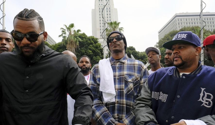 In this Friday, July 8, 2016, file photo, rappers The Game, left, and Snoop Dogg, center, appear at a peaceful unification march outside of the graduation ceremony for the latest class of Los Angeles Police Department recruits, in Los Angeles. (AP Photo/Richard Vogel, File)