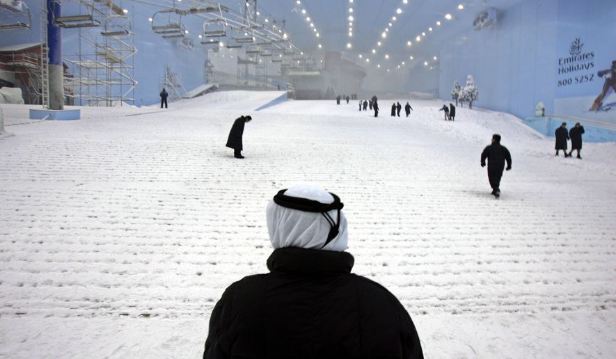 FILE - In this Oct. 25, 2005 file photo, Younis Al Mulla, General manager of Mall of the Emirates & Ski Dubai stands (with back to camera) viewing the snow covered slope at Ski Dubai complex as they have started to make real snow to prepare for the launch of first ski season in Dubai, United Arab Emirates. Visitors to Dubai have a new way to keep cool during the scorching Mideast summer. The company behind the city’s indoor ski slope plans to let guests stay overnight in tents on the man-made snow on Fridays starting from July 29, 2016. (AP Photo/Kamran Jebreili, File)