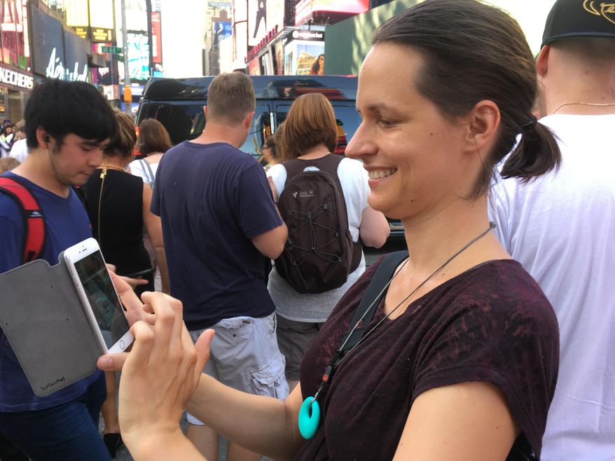 In this Thursday, July 14, 2016, photo, Associated Press reporter Barbara Ortutay plays "Pokemon Go" while walking through New York's Times Square. The game has become a virtual tour guide, pointing to places you might have overlooked with your gaze stuck to your phone. (AP Photo/Anick Jesdanun)