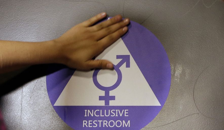 A new sticker is placed on the door at the ceremonial opening of a gender neutral bathroom at Nathan Hale High School in Seattle. (Associated Press) ** FILE **
