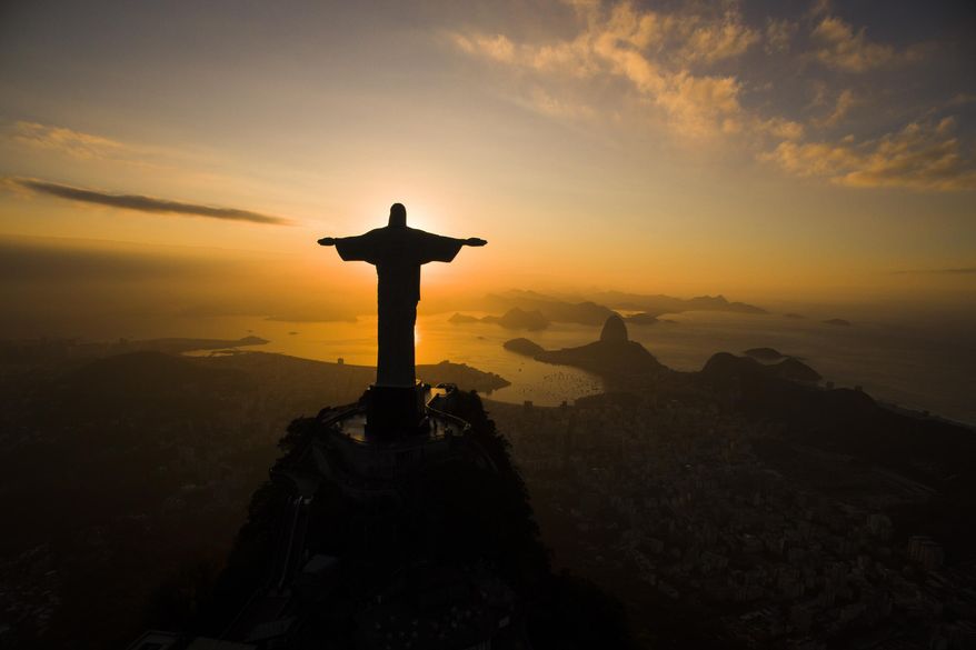 The sun rises behind the Christ the Redeemer statue, above the Guanabara bay in Rio de Janeiro, Brazil, Tuesday, July 19, 2016. (AP Photo/Felipe Dana)