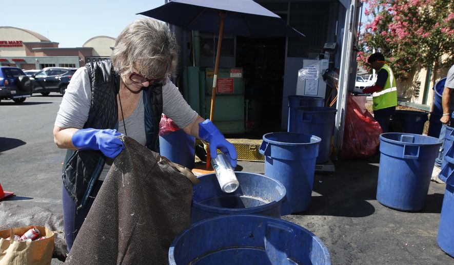 In this photo taken Tuesday, July 5, 2016 Claudette Cole places a plastic bottle into a plastic container at a recycling center in Sacramento, Calif. More than 450 recycling centers statewide have closed in the last year, stripping millions of consumers of easy access to recycling services. (AP Photo/Rich Pedroncelli)