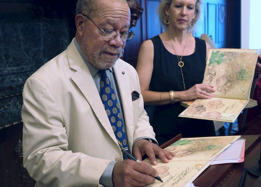 Children's book illustrator Jerry Pinkney, left, signs a copy of his book “The Lion and the Mouse” as Philadelphia's first deputy city representative, Margaret Hughes, watches Tuesday, July 19, 2016, at City Hall in Philadelphia. As Pinkney was honored by Philadelphia city officials Tuesday, July 19, 2016, he said his hometown of Philadelphia and African-American history play powerful roles in his career illustrating more than 100 children's books. (AP Photo/Dake Kang)