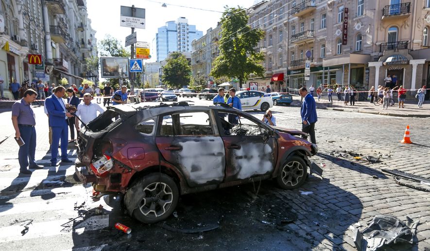 Forensic experts examine the wreckage of a burned car in Kiev, Ukraine, Wednesday, July 20, 2016. Pavel Sheremet, 44-year old Belarusian-born prominent journalist was killed in a car bombing in Ukraine&#x27;s capital Kiev. (AP Photo/Sergei Chuzavkov)