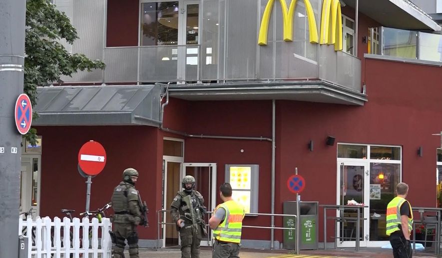 In this grab taken from video, police officers stand outside a McDonald&#39;s restaurant, near the mall, in Munich, Germany, Friday, July 22, 2016. A manhunt was underway Friday for a shooter or shooters who opened fire at a shopping mall in Munich, killing and wounding several people, a Munich police spokeswoman said. The city transit system shut down and police asked people to avoid public places. (NONSTOP NEWS via AP)