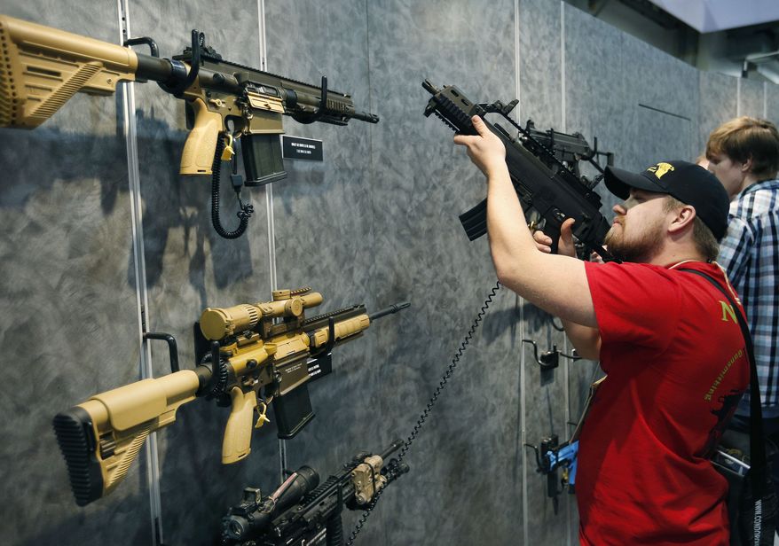 In this Jan. 19, 2016, file photo, Nolan Hammer looks at a gun at the Heckler & Koch booth at the Shooting, Hunting and Outdoor Trade Show in Las Vegas. (AP Photo/John Locher, File)