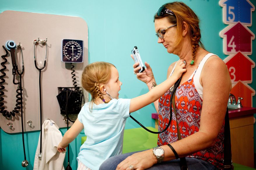 ADVANCE FOR USE SATURDAY, JULY 23 - In this photo taken July 6, 2016, Eliza Morgan,left, plays doctor with Stephanie Morgan at the Omaha Children's Museum in Omaha, Neb. The museum is now celebrating its 40th anniversary and has welcomed thousands upon thousands of tiny guests through its doors in its decades of service. (Sarah Hoffman/Omaha World-Herald via AP)