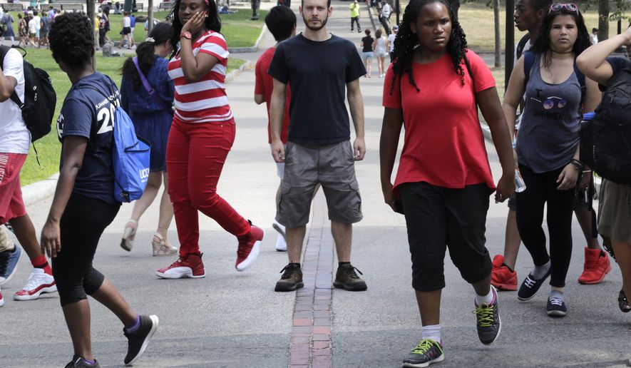 In this Friday, July 22, 2016 photo, Collin Allen, the creator of &#39;White Men for Black Lives&#39;, poses on the Freedom Trail in Boston Common, as a group of summer camp children walk past, in Boston, Mass. Some white Americans say they&#39;re being spurred to action by the shootings of black men by officers in Minnesota and Louisiana after long sitting in silence. (AP Photo/Charles Krupa)