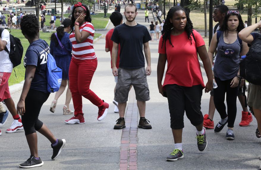 In this Friday, July 22, 2016 photo, Collin Allen, the creator of 'White Men for Black Lives', poses on the Freedom Trail in Boston Common, as a group of summer camp children walk past, in Boston, Mass. Some white Americans say they're being spurred to action by the shootings of black men by officers in Minnesota and Louisiana after long sitting in silence. (AP Photo/Charles Krupa)