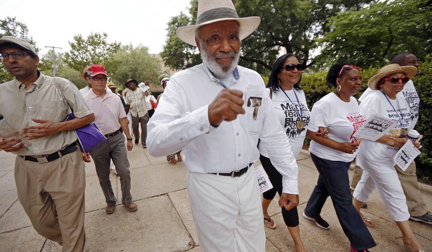 In this June 25, 2016 photo, civil rights pioneer James Meredith, center, and others walk through downtown Jackson, Miss., to the state Capitol, as part of a 50th commemoration of his march from Memphis to Jackson to encourage black people to overcome a fear of violence and to encourage them to register to vote. Along the way, he was shot and wounded, causing several groups and hundreds of marchers, including the Rev. Martin Luther King Jr., to take up the cause and help him finish the march to the Capitol. (AP Photo/Rogelio V. Solis)
