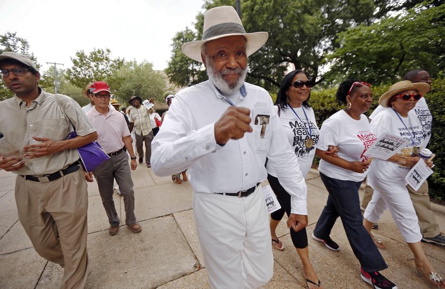 In this June 25, 2016 photo, civil rights pioneer James Meredith, center, and others walk through downtown Jackson, Miss., to the state Capitol, as part of a 50th commemoration of his march from Memphis to Jackson to encourage black people to overcome a fear of violence and to encourage them to register to vote. Along the way, he was shot and wounded, causing several groups and hundreds of marchers, including the Rev. Martin Luther King Jr., to take up the cause and help him finish the march to the Capitol. (AP Photo/Rogelio V. Solis)
