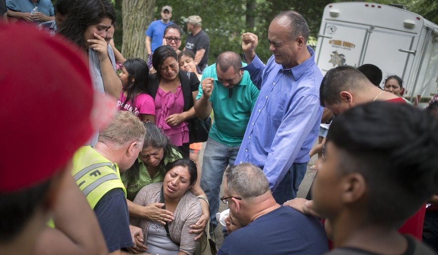 A family member of the victim who has drowned is aided by emergency personnel, church and other family members, while crying out in prayer after emergency personnel discovered the missing body at Crockery Lake in Chester Township, Mich., Sunday, July 24, 2016. (Tom Brenner/The Grand Rapids Press-MLive.com via AP)