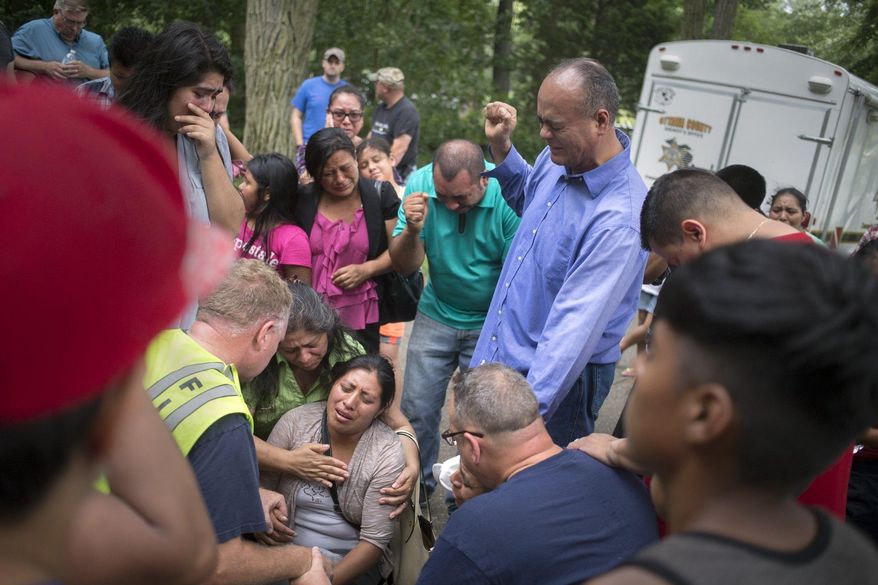 A family member of the victim who has drowned is aided by emergency personnel, church and other family members, while crying out in prayer after emergency personnel discovered the missing body at Crockery Lake in Chester Township, Mich., Sunday, July 24, 2016. (Tom Brenner/The Grand Rapids Press-MLive.com via AP)