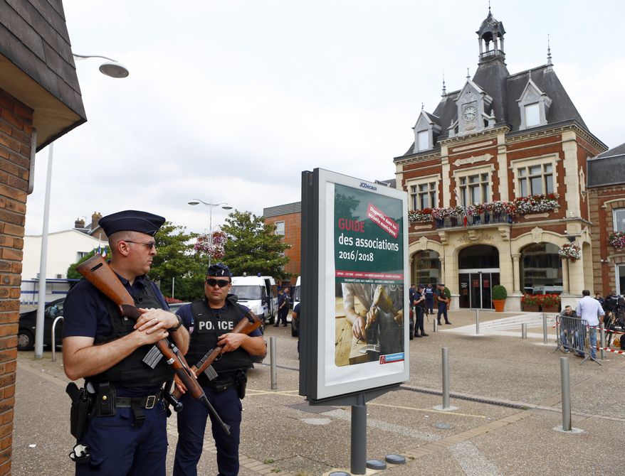 French police officers stand guard in front of the Saint-Etienne-du-Rouvray's city hall, Normandy, France, after an attack on a church that left a priest dead, Tuesday, July 26, 2016. Two attackers invaded a church Tuesday during morning Mass near the Normandy city of Rouen, killing an 84-year-old priest by slitting his throat and taking hostages before being shot and killed by police, French officials said. (AP Photo/Francois Mori)