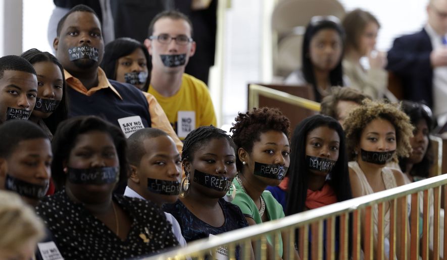Members of North Carolina student chapters of the NAACP and opponents of voter ID legislation wear tape over their mouths while sitting silently in the gallery of the House chamber of the North Carolina General Assembly where lawmakers debated and voted on voter identification legislation in Raleigh, N.C., on April 24, 2013. (Associated Press) **FILE**