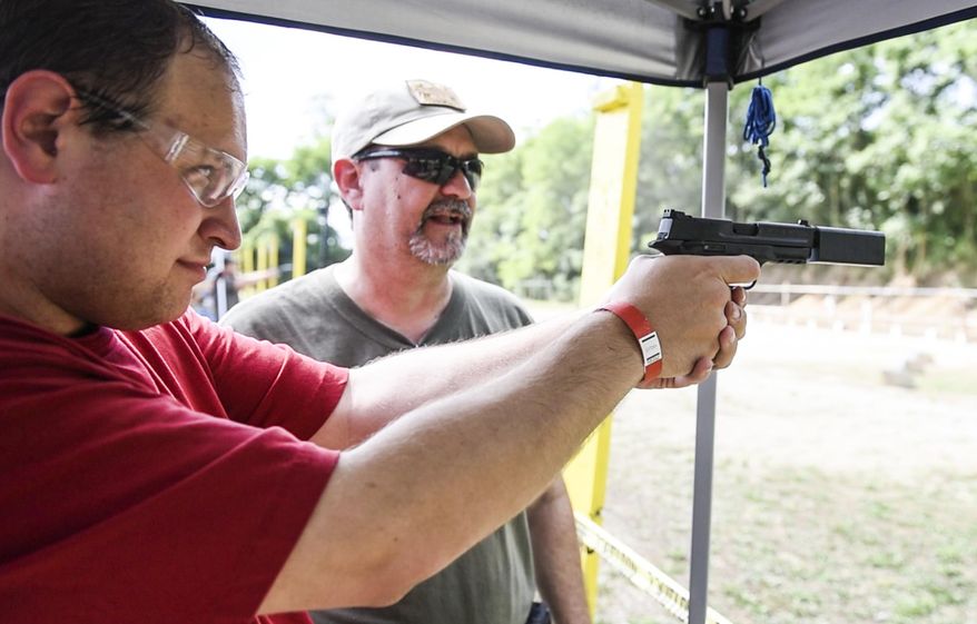 FOR RELEASE SATURDAY, JULY 30, 2016, AT 3:01 A.M. EDT. - Daniel Walmer, a reporter for the Lebanon Daily News, shoots a Smith & Wesson .22 compact pistol with a Silencerco Osprey Micro suppressor at Lanco Tactical's Suppressor Day at the Lebanon County Police Combat Pistol Club on Sunday, July 10, 2016.( Jeremy Long/Lebanon Daily News via AP)