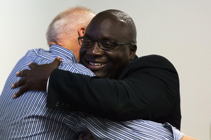 Kalamazoo City Commissioner David Anderson, left, embraces Kalamazoo City Mayor Bobby Hopewell during a Kalamazoo City Commission meeting at Kalamazoo Metro Transit in Kalamazoo, Mich. on Thursday, July 28, 2016. The meeting was held to talk about revenue options for the city of Kalamazoo. (Bryan Bennett/Kalamazoo Gazette-MLive Media Group via AP)