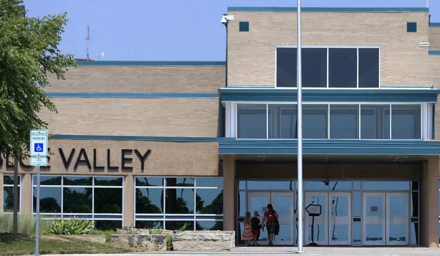 FILE - In this Monday June 20, 2016 file photo, a family approaches the front doors at Blue Valley Northwest High School in Overland Park, Kan. Blue Valley had fewer than 900 students in 1970. It is now the state's fourth-largest district, with more than 22,500 students and five high schools, the newest one opening in 2010. (AP Photo/Orlin Wagner, file)