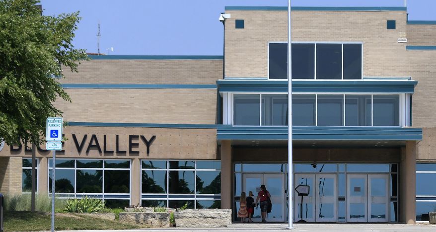 FILE - In this Monday June 20, 2016 file photo, a family approaches the front doors at Blue Valley Northwest High School in Overland Park, Kan. Blue Valley had fewer than 900 students in 1970. It is now the state's fourth-largest district, with more than 22,500 students and five high schools, the newest one opening in 2010. (AP Photo/Orlin Wagner, file)