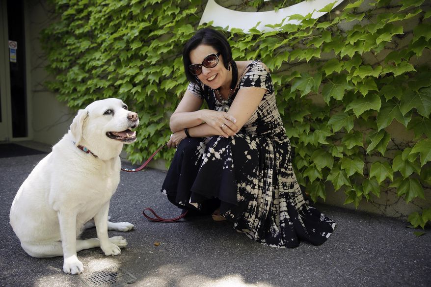 In this photo taken Tuesday, May 31, 2016, Emma Swain, CEO of St. Supery Vineyards and Winery poses with GG, the CCO or Chief Cuddle Officer, outside the winery's tasting room in Rutherford, Calif. For those who love their dogs and their wine, there are now a number of Napa Valley wineries where you don't have to choose between the two because canines are allowed in the tasting rooms. (AP Photo/Eric Risberg)