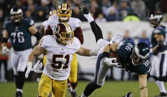 Philadelphia Eagles&#x27; Zach Ertz (86) is tackled by Washington Redskins&#x27; DeAngelo Hall (23) and Will Compton (51) in the first half of an NFL football game, Saturday, Dec. 26, 2015, in Philadelphia.  (AP Photo/Michael Perez)