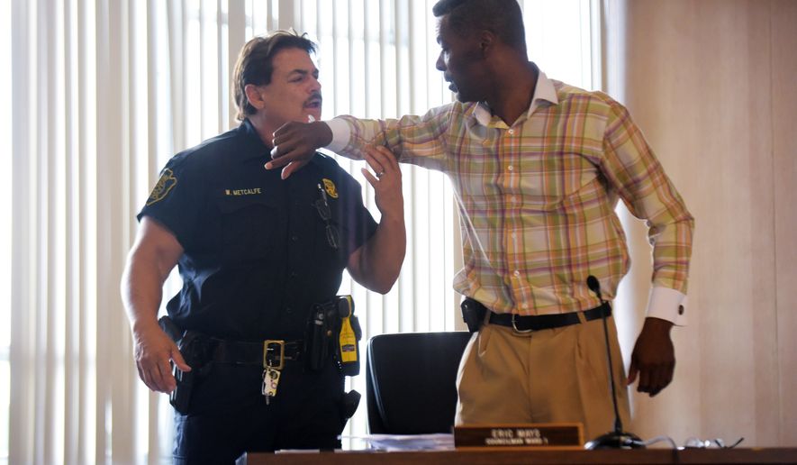 Councilman Eric Mays, right, is put in handcuffs by Flint police officer William Metcalfe, left, after being after being asked to leave by council president Kerry Nelson or being disruptive at the Flint City Hall Monday, Aug. 1, 2016, in Flint. The Flint City Council held a special meeting to discuss a recent lawsuit surrounding the city's controversial trash contract. Garbage collection in Flint will resume Tuesday after a one-day suspension as a trash hauler agreed to a temporary deal and residents fumed over the controversy between the mayor and City Council. (Mark Felix/The Flint Journal-MLive.com via AP)