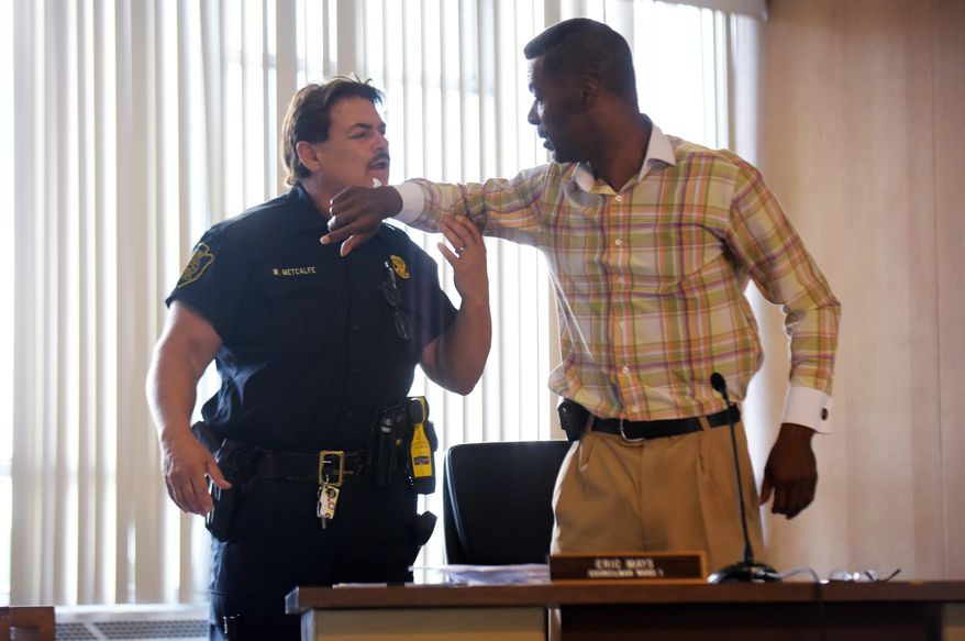 Councilman Eric Mays, right, is put in handcuffs by Flint police officer William Metcalfe, left, after being after being asked to leave by council president Kerry Nelson or being disruptive at the Flint City Hall Monday, Aug. 1, 2016, in Flint. The Flint City Council held a special meeting to discuss a recent lawsuit surrounding the city's controversial trash contract. Garbage collection in Flint will resume Tuesday after a one-day suspension as a trash hauler agreed to a temporary deal and residents fumed over the controversy between the mayor and City Council. (Mark Felix/The Flint Journal-MLive.com via AP)