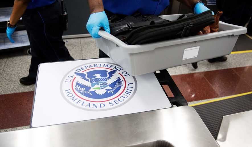 A U.S. Department of Homeland Security seal is seen as a TSA official moves a bin for additional screening at a newly designed passenger screening lane unveiled at Hartsfield-Jackson Atlanta International Airport. (AP Photo/David Goldman)