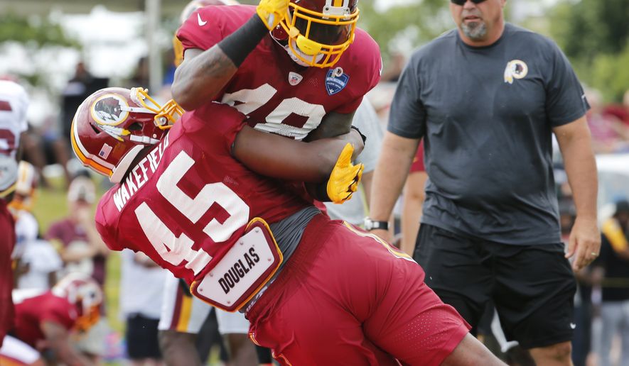 Washington Redskin linebacker Mike Wakefield (45) practices tackling Lynden Trail (48) under the watchful eye of a coach during the afternoon practice at NFL football training camp in Richmond, Va., Tuesday, Aug. 2, 2016. (AP Photo/Steve Helber)