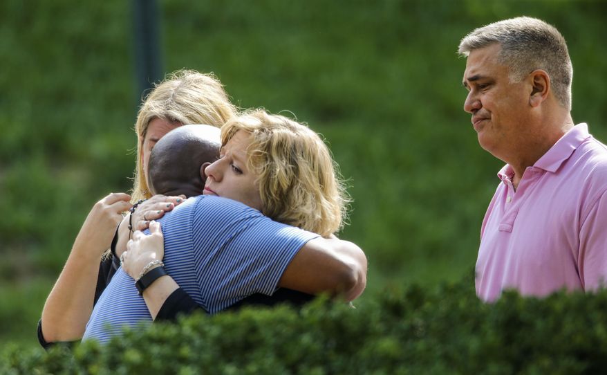 People hug near a crime scene, Tuesday, Aug. 2, 2016 in Roswell, Ga. Detectives on Tuesday were combing through video from multiple cameras and hoping to hear from any possible witnesses near a suburban Atlanta grocery store in the pre-dawn hours before a teenage boy and girl were both found slain, authorities said. The bodies of Natalie Henderson and Carter Davis, both 17, were discovered by a delivery driver behind the Publix supermarket shortly before 6 a.m. Monday, Roswell police said. (John Spink/Atlanta Journal-Constitution via AP)