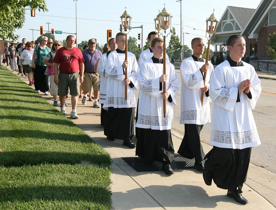 In this July 17, 2016 photo, a group of servants lead a procession in Quincy, Ill., to mark the 130th anniversary of Father Augustus Tolton's return to the city after his studies and ordination in Rome. When the Rev. Tolton returned to Quincy in 1886, hundreds of Quincyans welcomed home the country's first recognized black priest with open arms. This years celebration, a much smaller, but no less reverent, crowd marked the anniversary with prayer and a procession to St. Peter Catholic Cemetery, where Tolton has been buried for almost 120 years. (Alyse Thompson/The Quincy Herald-Whig via AP)