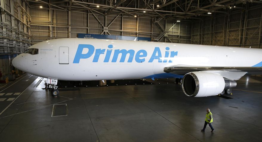A worker walks past a Boeing 767 with an Amazon.com "Prime Air" livery on display Thursday, Aug. 4, 2016, in a Boeing hangar in Seattle. Amazon unveiled its first branded cargo plane Thursday, one of 40 jetliners that will make up Amazon's own air transportation network of 40 Boeing jets leased from Atlas Air Worldwide Holdings and Air Transport Services Group Inc., which will operate the air cargo network. (AP Photo/Ted S. Warren)