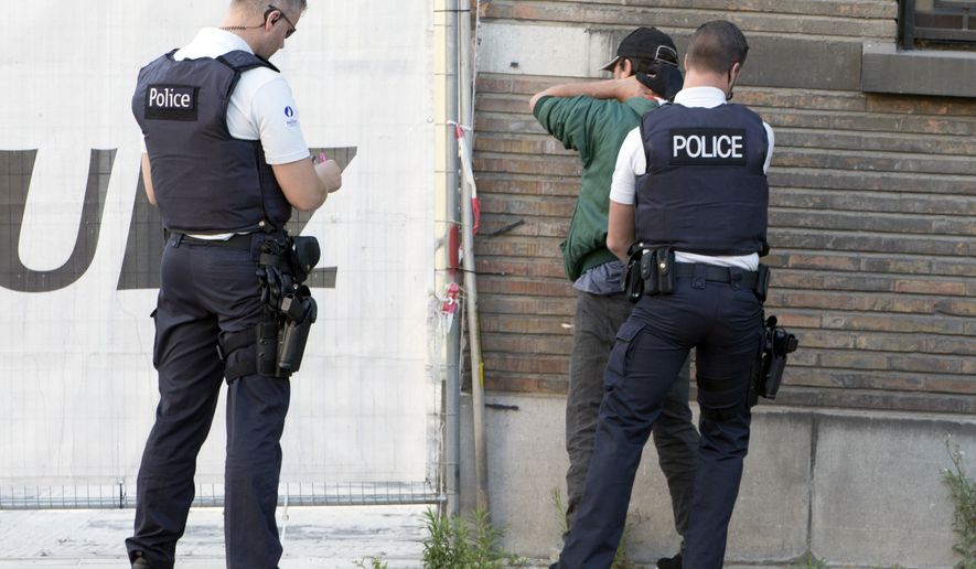 Police officers check identification of a man near the police headquarters in Charleroi, Belgium on Saturday, Aug. 6, 2016, following a machete attack in the area.  A man attacked two police officers with a weapon near the headquarters on Saturday before being apprehended. (AP Photo/Virginia Mayo)