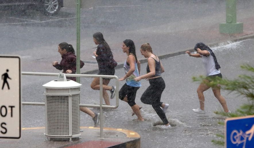 Several young women get drenched as they race through the rain at the University of Arizona Tuesday, Aug. 9, 2016, in Tucson, Ariz. Heavy rain associated with Tropical Storm Javier in Mexico fell over the American Southwest. (A.E. Araiza/Arizona Daily Star via AP)
