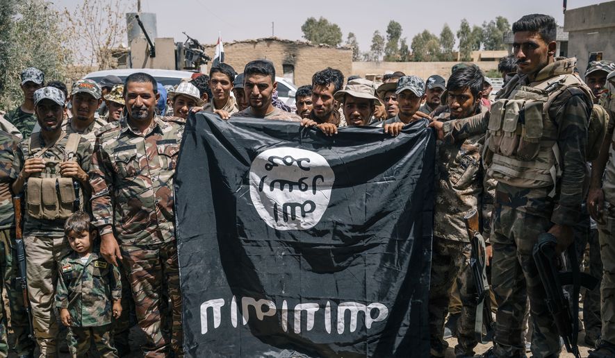 Sheikh Nazhan Sakhar, second from the right, poses for a picture with his men holding an Islamic State flag they captured in Hajj Ali, Iraq, Tuesday, August 9, 2016. Sheikh Nazhan Sakhar and the 700 men under his command are among the forces preparing to retake the Iraqi city of Mosul from the Islamic state group. He says his Sunni militia is critical to defeating IS and maintaining peace afterward because his fighters, unlike the majority of Iraq&#39;s military, are local to Mosul. (AP Photo/Alice Martins)
