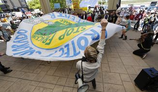 Protesters wave a banner during an attempt to disrupt a federal auction of drilling rights at a hotel in Lakewood, Colorado, on May 12. More than 200 people turned out to protest the Bureau of Land Management sale. (Associated Press)