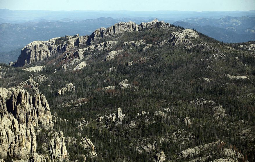 FILE - This Aug. 14, 2014, aerial file photo shows Harney Peak southwest of Hill City, S.D. The recent decision by the U.S. Board on Geographic Names to rename Harney Peak to Black Elk Peak surprised South Dakota's governor, but vindicated activists who unsuccessfully argued to state officials last year that the peak in the Black Hills shouldn't bear the name of a man whose soldiers killed Native Americans. (Chris Huber/Rapid City Journal via AP, File)