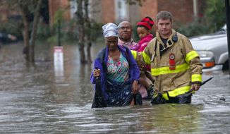 A member of the St. George Fire Department assists residents as they wade through floodwaters from heavy rains in the Chateau Wein Apartments in Baton Rouge, La., Friday, Aug. 12, 2016. (AP Photo/Gerald Herbert)