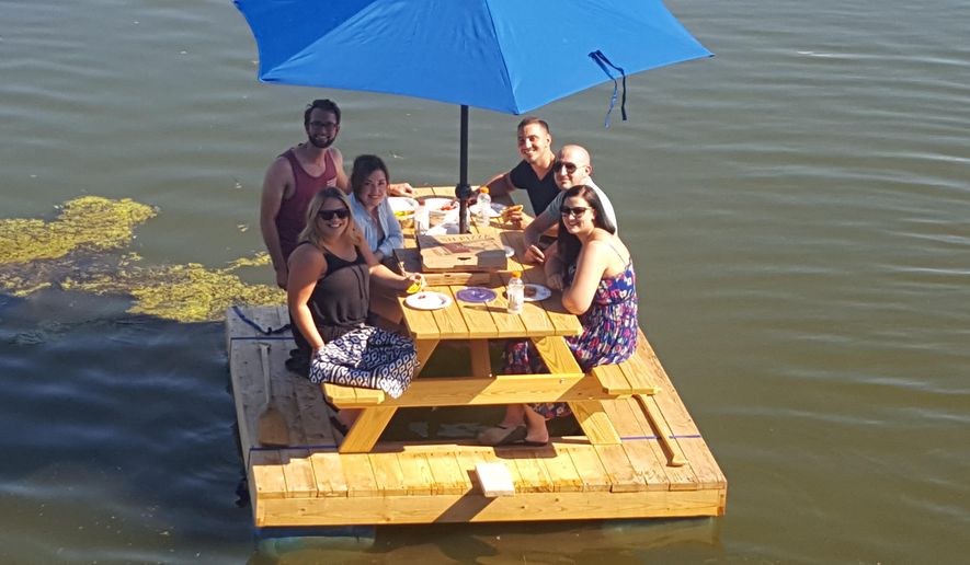 In an Aug. 7, 2016 photo, Caleb Keller, rear right, and his wife, Meagan, front left, enjoy a ride on their picnic table boat with a group of friends on Speedwell Forge Lake, in Lancaster, Pa. (Keith Schweigert/LNP Media Group, Inc. via AP)